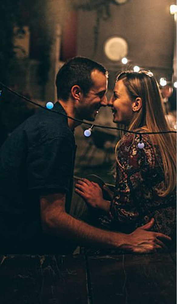 couple-nuzzling-at-small-scale-concert-with-bistro-lights
